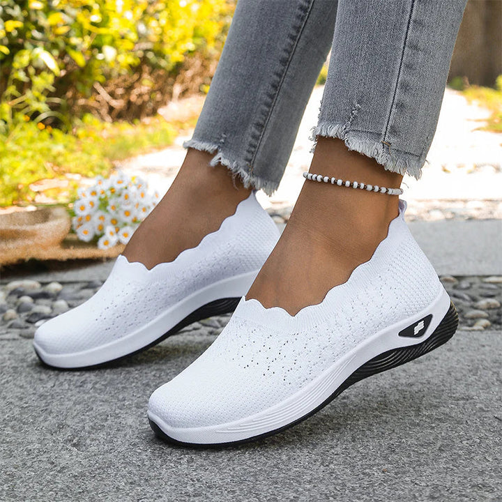 Hvide strikkede slip-on sko med bølget kant båret af model udendørs, med perlearmbånd om anklen 21