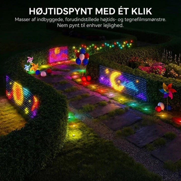 Små lysgardiner med farvede mønstre og lyspunkter langs en havesti med hække og farverige dekorationer om natten 7