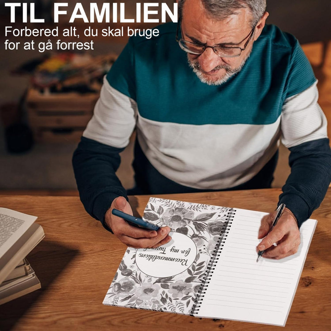 Ældre mand med briller ved et træbord, der skriver i den opslåede planlægger med en kuglepen, mens han holder en mobiltelefon i den anden hånd. 4