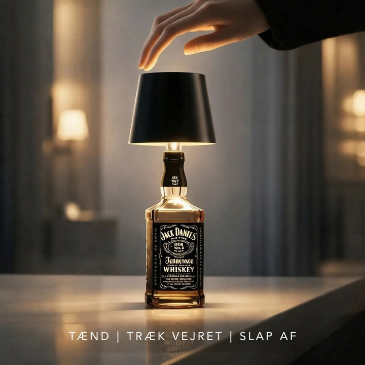 En hånd rører øverst på den sorte flaskelampe, der lyser på en whiskyflaske 6