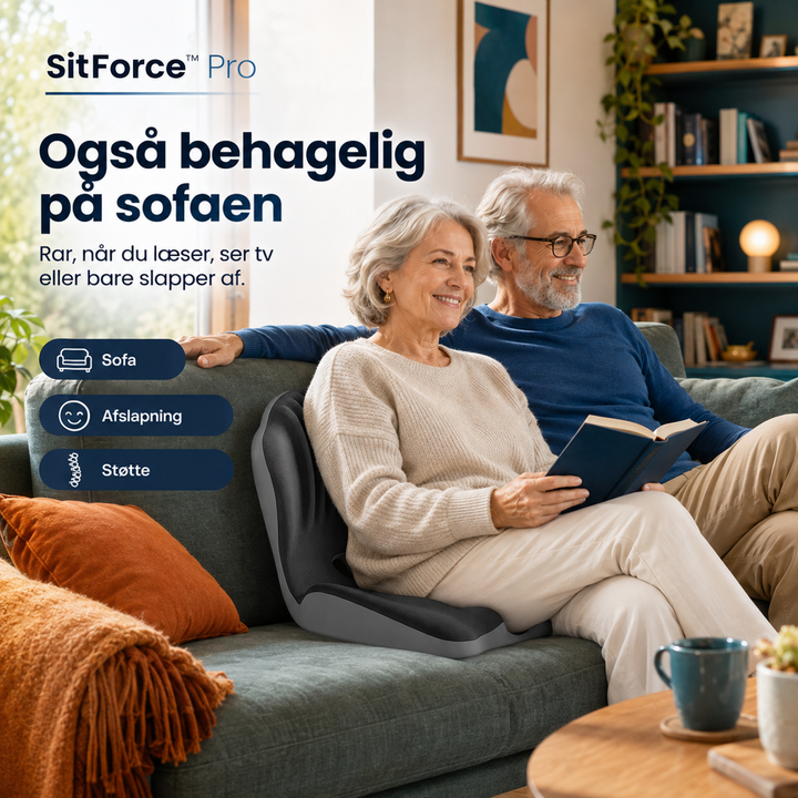 Ældre par i sofaen, hvor kvinden læser en bog med det mørkegrå sædehynde bag ryggen 2