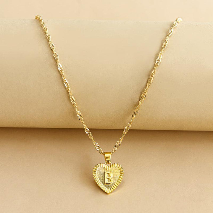Goldene Herz-Halskette mit Buchstabenanhänger, gedrehtes Kettendesign, eleganter Schmuck.