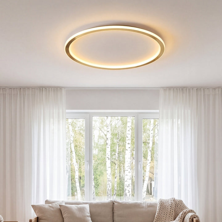 Tændt ringlampe i loftet i en stue med hvide gardiner og sofa foran vinduet 3