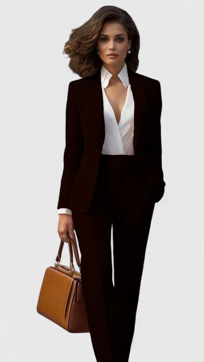 Model i mørkt, næsten sort sæt med blazer og bukser, hvid skjorte og brun håndtaske i hånden. 7