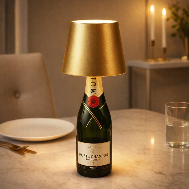 Guldfarvet flaskelampe på en champagneflaske på et marmorbord med tallerken, glas og stearinlys 17
