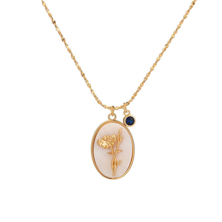 Goldene Halskette mit ovalem Anhänger, Blumenmotiv, blauer Stein, eleganter Schmuck.