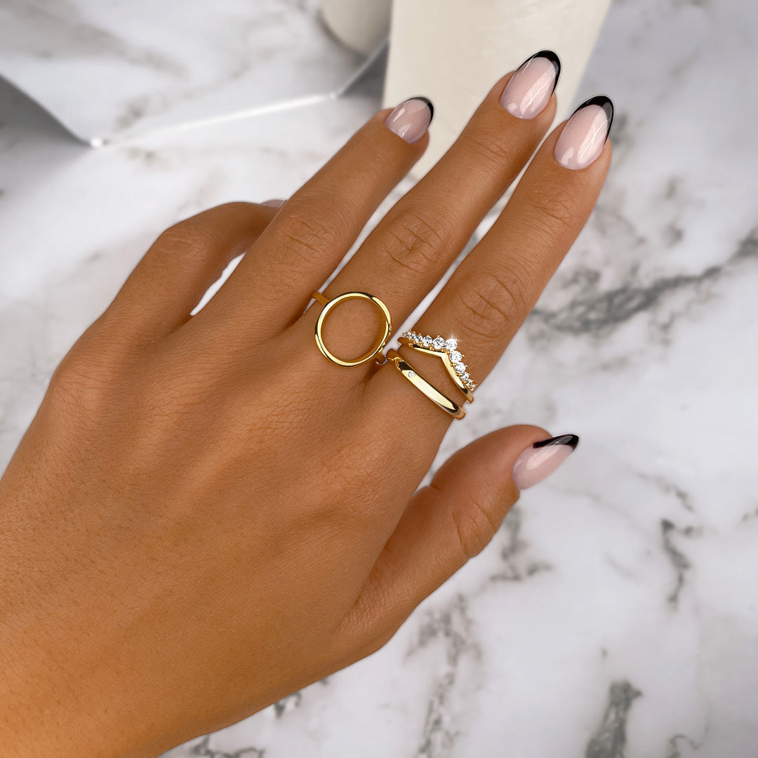Goldene Ringe auf Hand mit französischer Maniküre, Marmorhintergrund, Schmuck, Modeaccessoire.