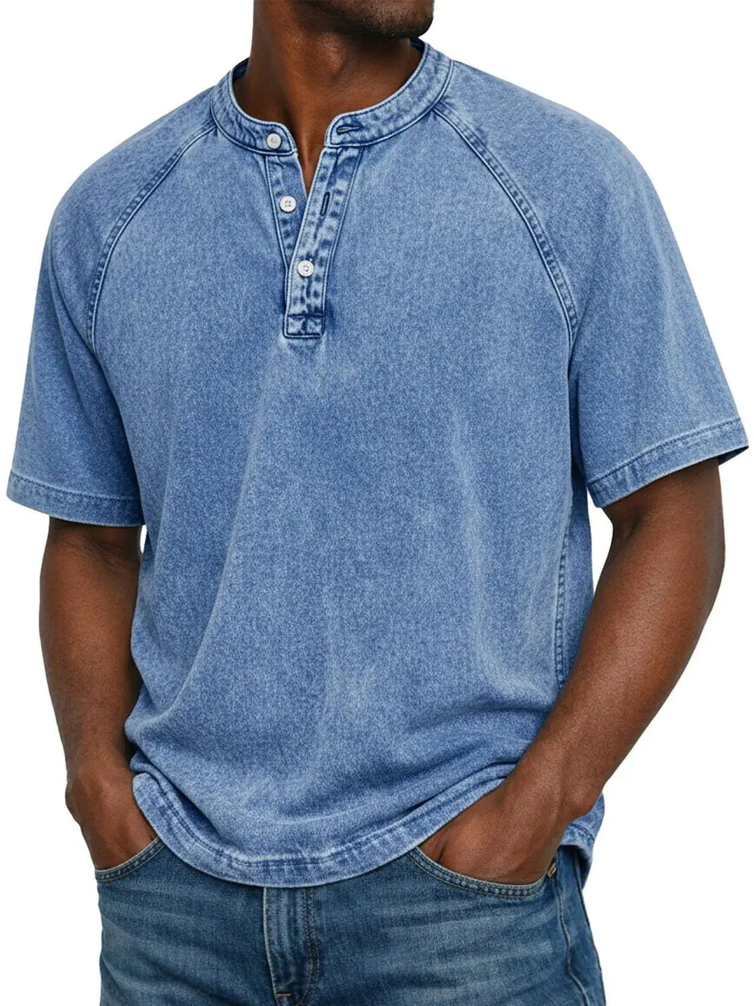 Mand i lyseblå vasket Henley-T-shirt med raglanærmer og tre knapper i halsen, kombineret med blå jeans. 2