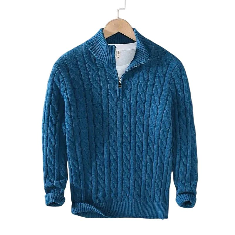 Dyb blå kabelstrikket trøje med kort lynlås og ribstrikket krave, hængende på en træbøjle med hvid t-shirt under. 5