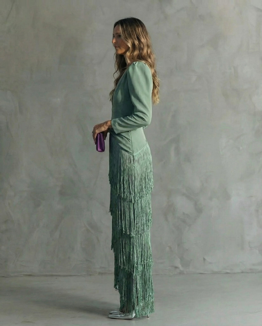 Sidebillede af model i grøn frynsekjole med puffærmer og lilla clutch i hænderne 3