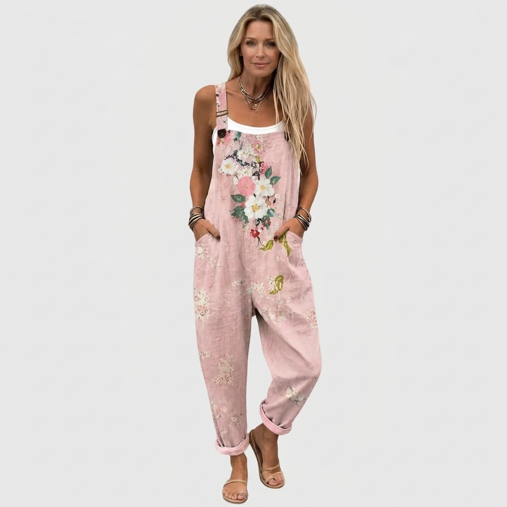 Model i fuld figur forfra i de lyserøde blomsterprintede overalls med hvid top indenunder, hænderne i lommerne og sandaler på. 2