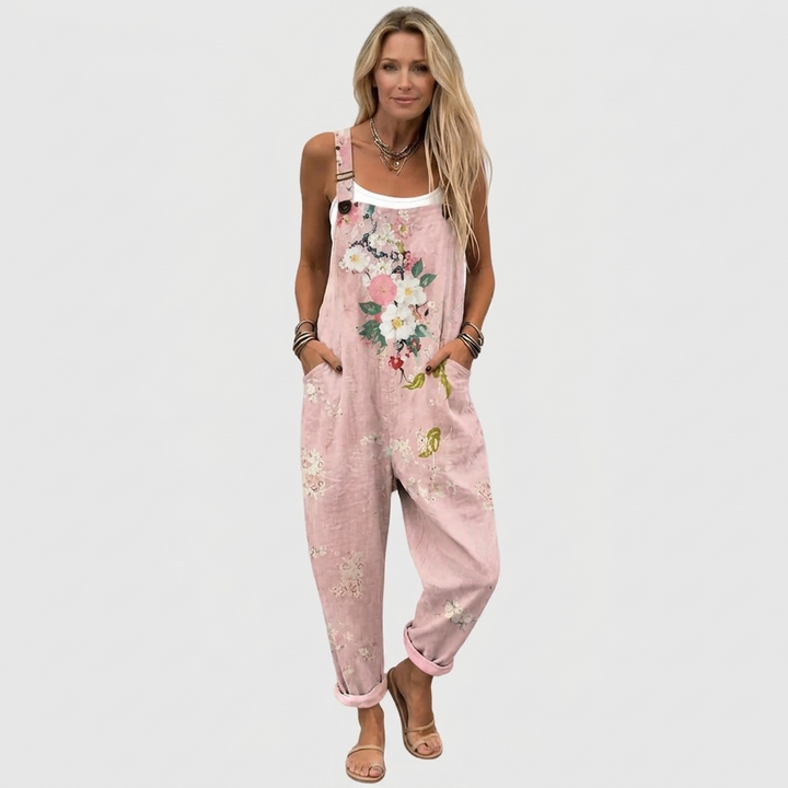 Model i fuld figur forfra i de lyserøde blomsterprintede overalls med hvid top indenunder, hænderne i lommerne og sandaler på. 2