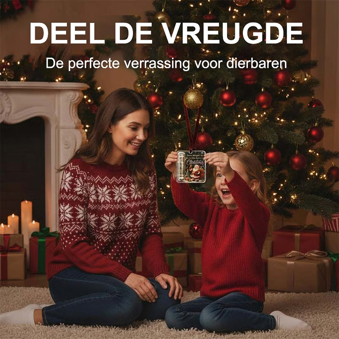Pige holder ophænget op foran juletræet, mens en kvinde i rød sweater sidder smilende ved siden af på tæppet. 3