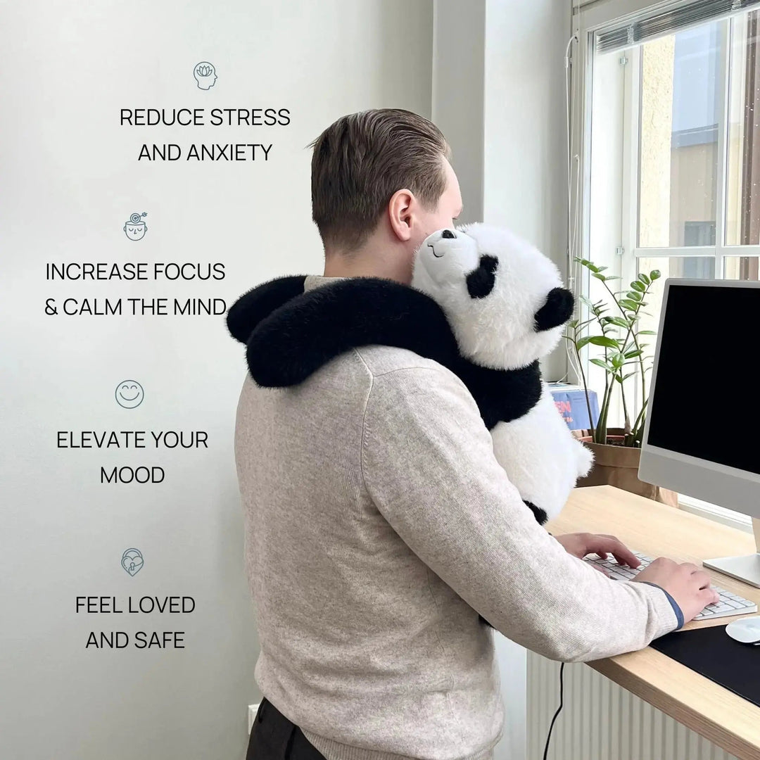 Mand ved computer i kontoret har panda-krammedyret med de lange arme lagt om skuldrene, mens han skriver. 2