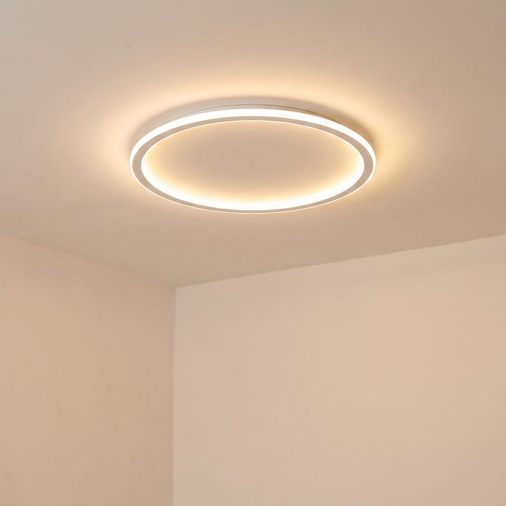 Tændt loftslampe set skråt nedefra i et hjørne med lyse vægge og blødt, varmt lys. 6