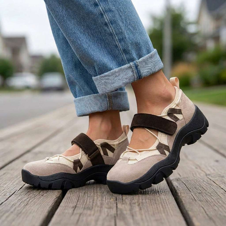 Beige sko med brun velcrostrop og sort sål, båret med oprullede jeans på en trækaj udendørs. 6