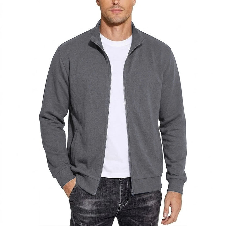 Mand i mørkegrå sweatshirtjakke med åben lynlås og opstående krave, set forfra med hånden i lommen. 5