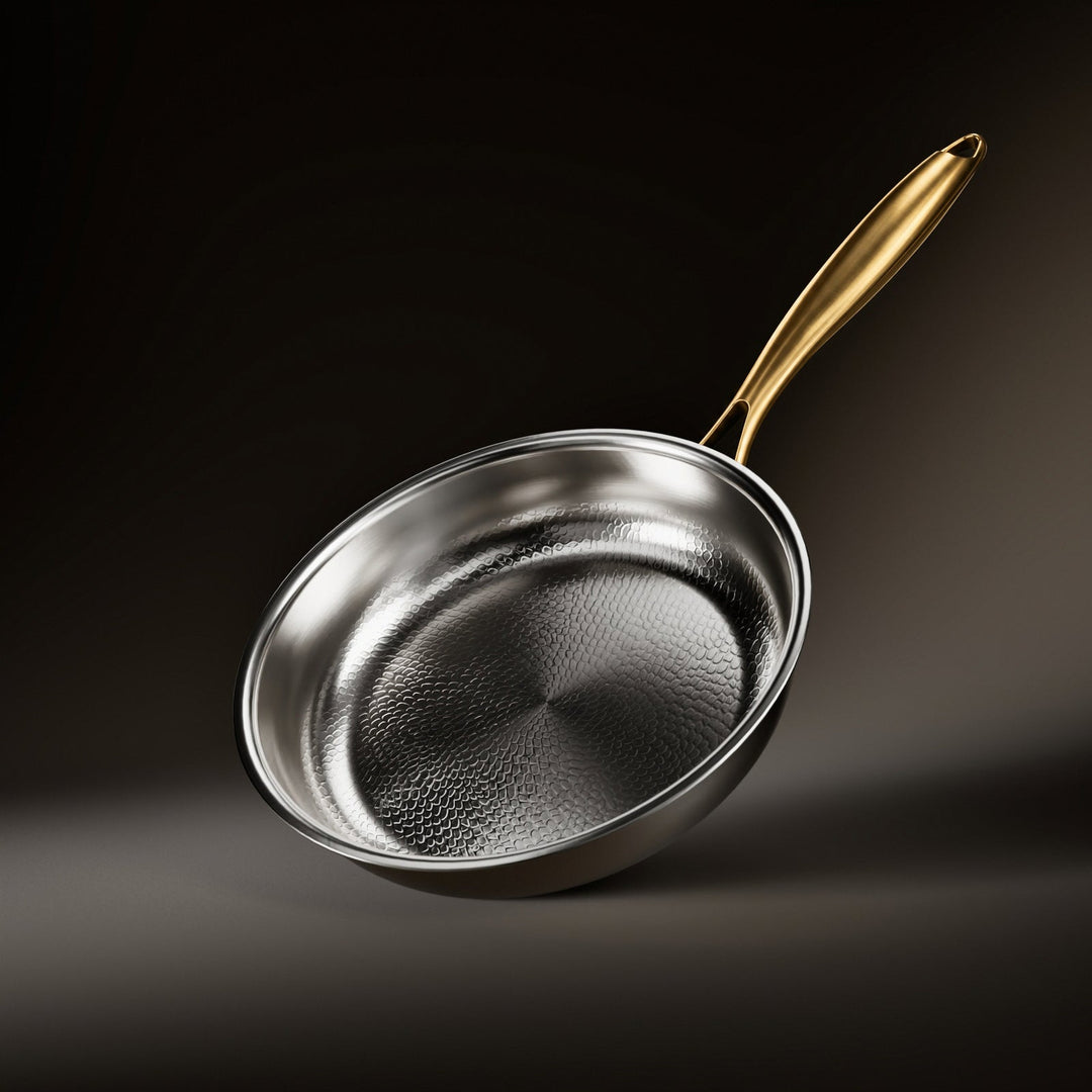 Stegepande set skråt ovenfra med håndhamret kogeflade i metal og langt skaft i børstet messing mod mørk baggrund. 1