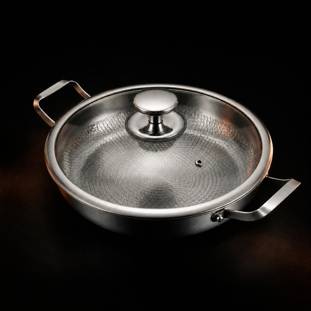 Pande med påsat glaslåg med metalknop og lille dampåbning, set skråt ovenfra mod sort baggrund. 4