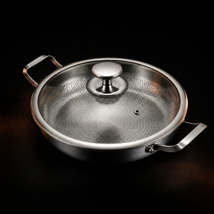 Pande med påsat glaslåg med metalknop og lille dampåbning, set skråt ovenfra mod sort baggrund. 4
