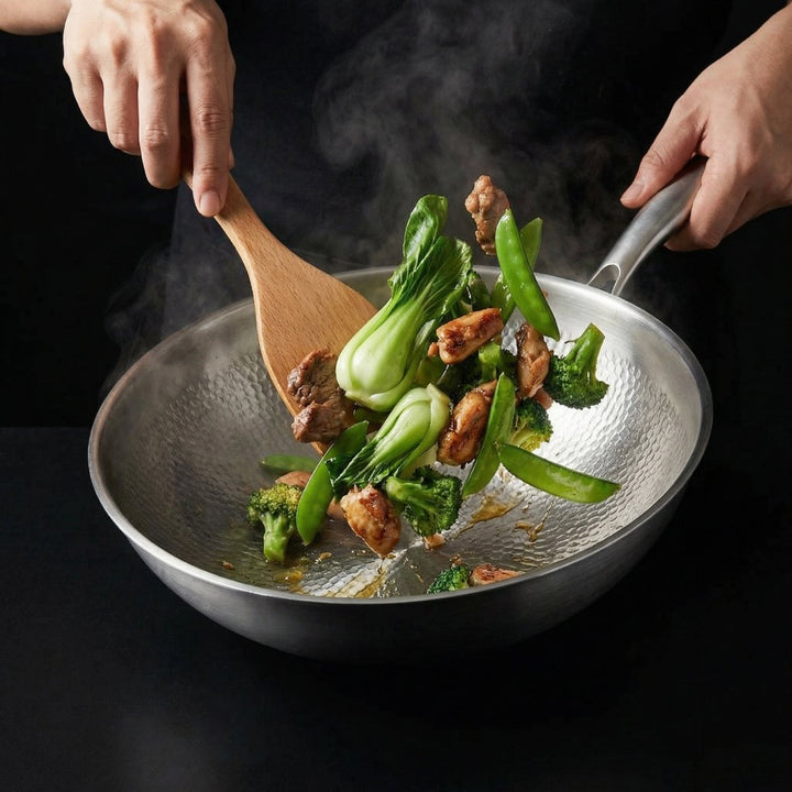 To hænder rører rundt i wokpanden med en træspatel, med kødstykker, pak choi, broccoli og sukkerærter og opstigende damp. 8
