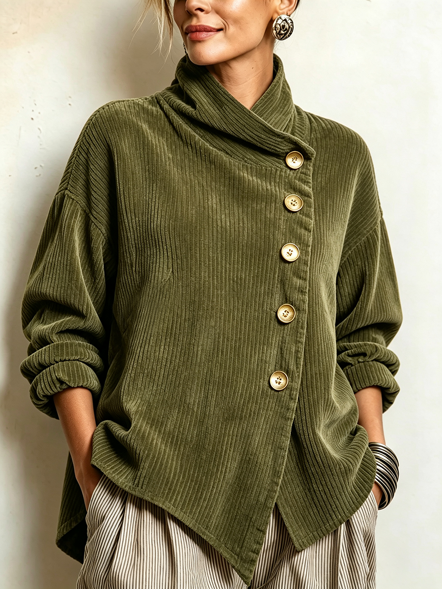 Nærbillede af den olivengrønne cordsweater med asymmetrisk knapstolpe, gyldne knapper og draperet krave, båret af en model mod en lys væg. 1