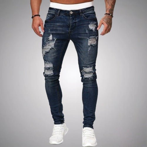 Model i mørkeblå slidte slim fit jeans med flossede huller på lår og knæ, set forfra med hvide sneakers. 4