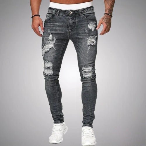 Model i grå slidte slim fit jeans med flossede huller på lår og knæ, set forfra med hvide sneakers. 5