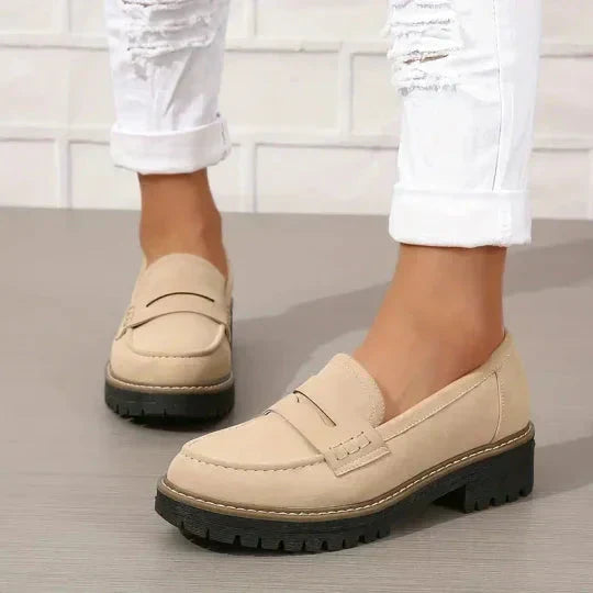 Lyse beige loafers med sort platformsål båret af model i hvide jeans med flænger, set fra siden. 7