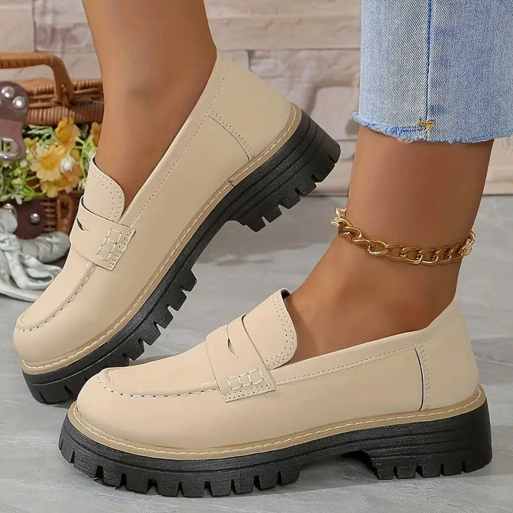 Cremebeige loafers med glat overflade og tyk sort platformsål, båret med guldfarvet ankelkæde og jeans. 14