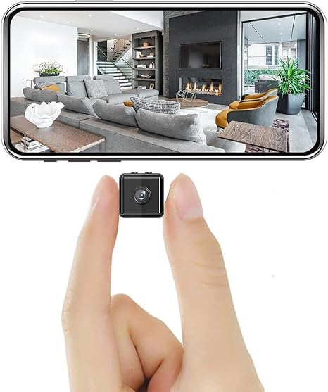 Det lille sorte kamera holdt mellem to fingre for at vise størrelsen, over en smartphone med live-billede af en stue. 1