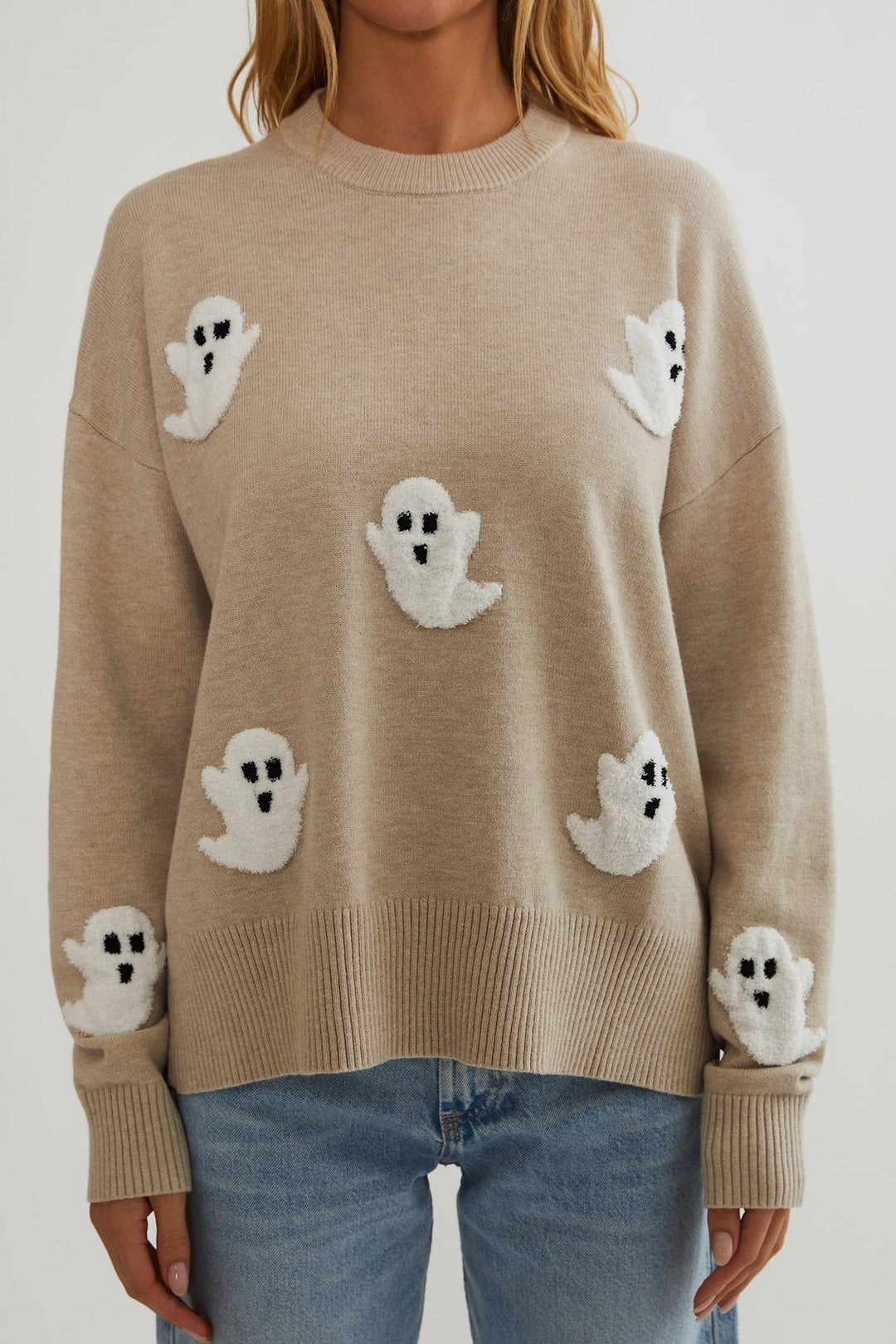 Nærbillede forfra af den beige sweater med hvide frottéagtige spøgelser på krop og ærmer, rund hals og ribstrikket kant. 2
