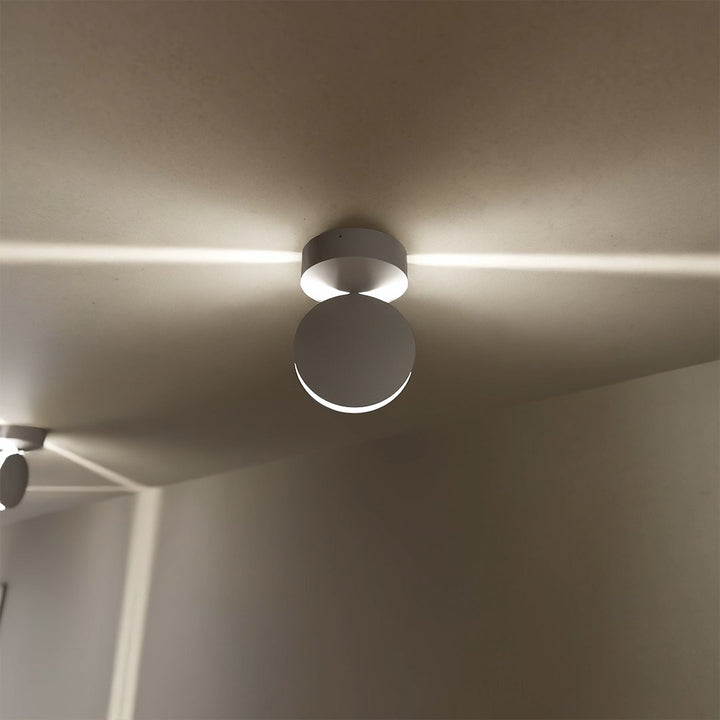 Nærbillede af en hvid loftlampe med rundt, drejeligt hoved, der sender en vandret lysstribe ud langs loftet. 3